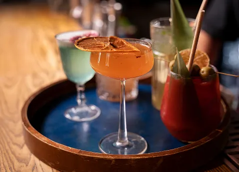 Cocktails latins colorés servis sur un plateau en bois au bar