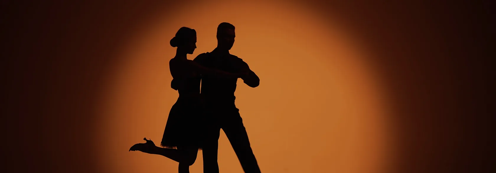 Couple dansant salsa silhouette contre coucher de soleil orange